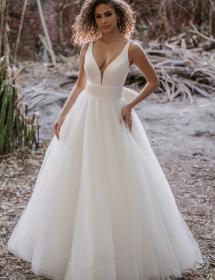 Woman is modeling a wedding dress in front of some sort of jungle