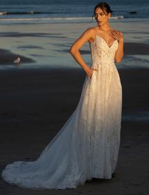 Model wearing a wedding dress on a beach.