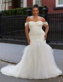 Happy model wearing a wedding gown in front of a row house with black iron fence protecting it.
