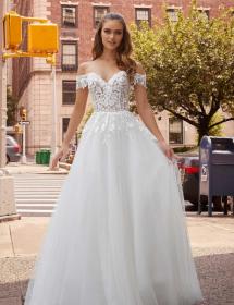 Model in a wedding dress is on a city street and waiting at a stoplight to cross the street.. 